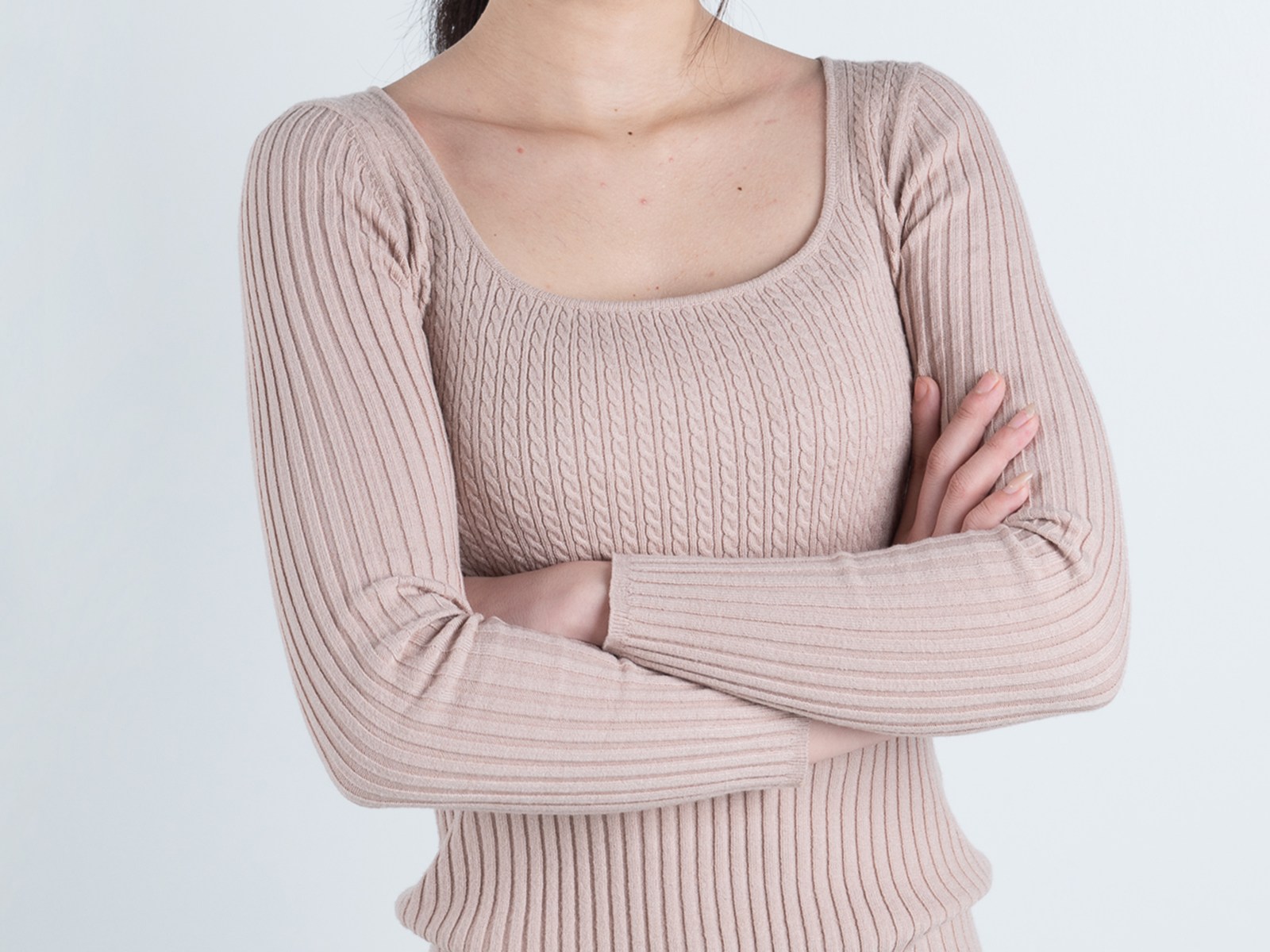 베이지색 상의를 입고 팔짱을 낀 여성의 참고용 스톡 이미지